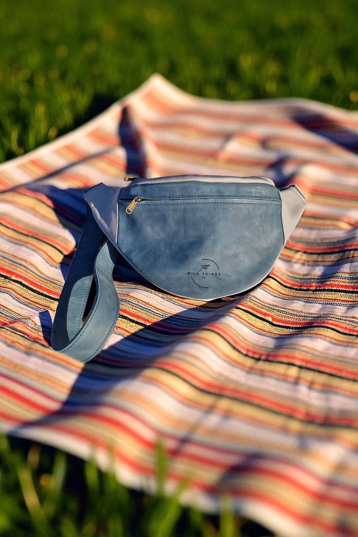 A custom two-tone Tiffany blue Harvest Moonbag laid on a striped picnic blanket
